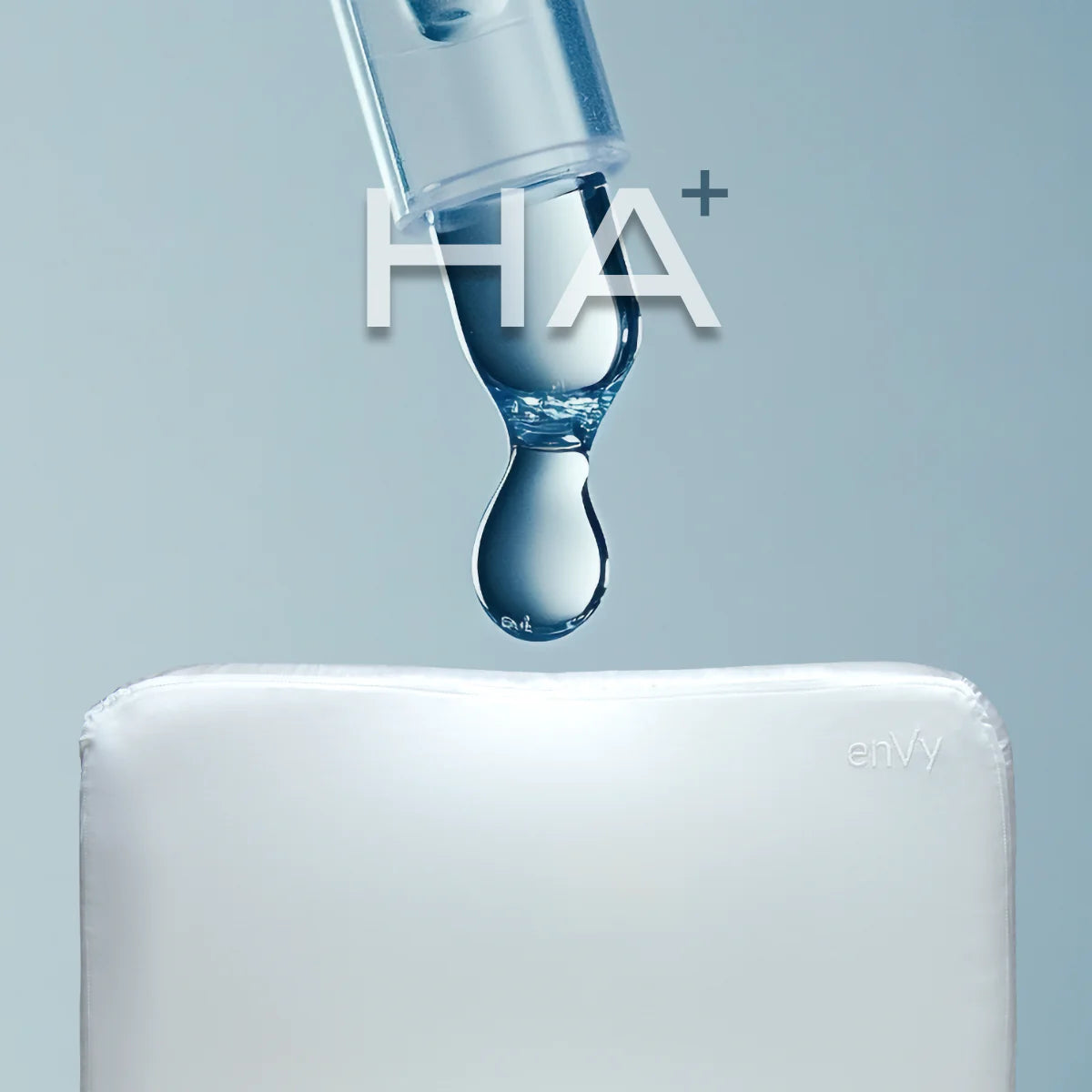 Hyaluronic acid HA+ serum dropper above enVy anti-aging pillow showing overnight skin hydration for beauty sleep