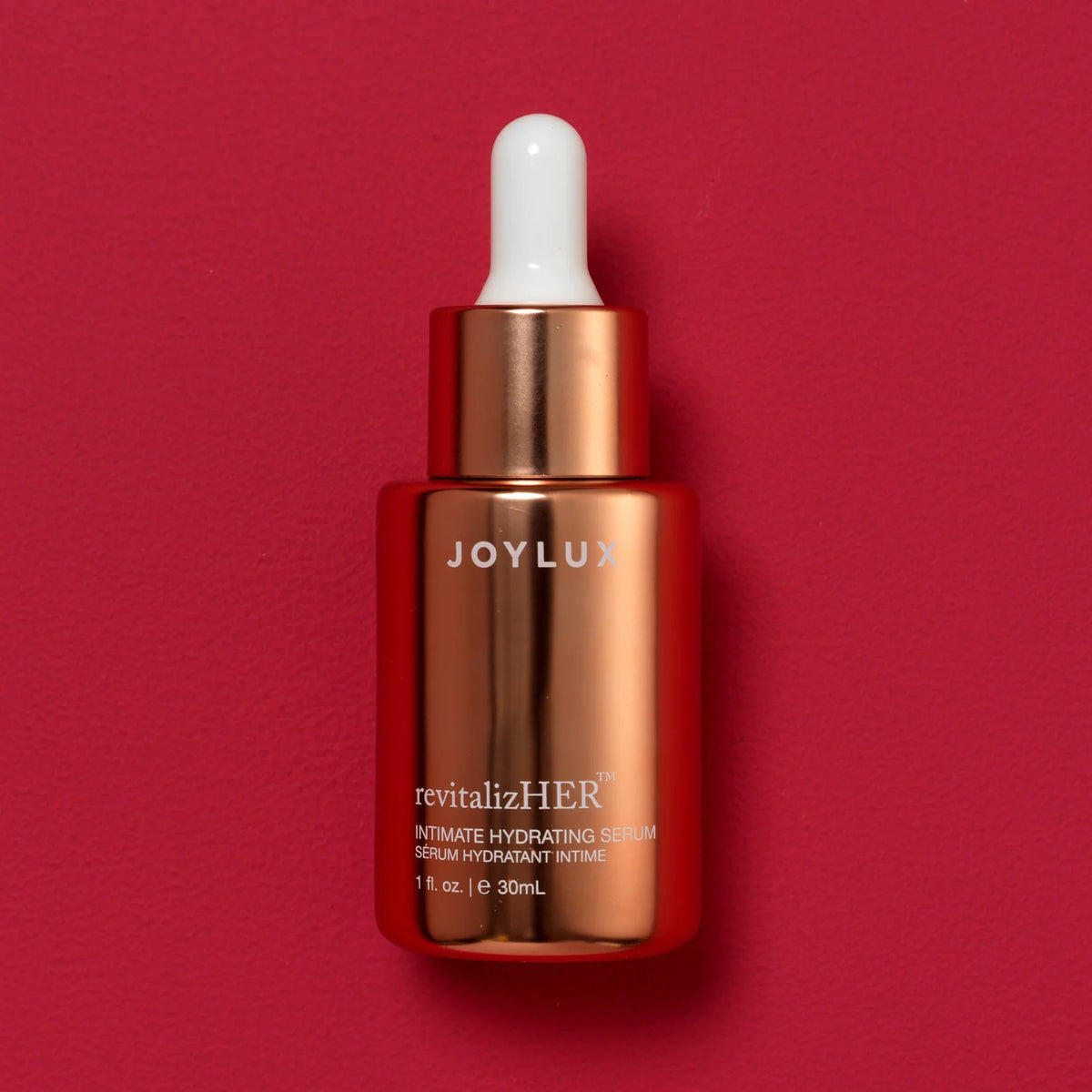 Joylux Revitalize-HER rose gold serum bottle on red background for intimate hydration and feminine comfort care