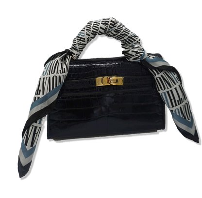 Nazarian ThinkBIG silk scarf tied around a black handbag handle with bold logo print and blue border detail