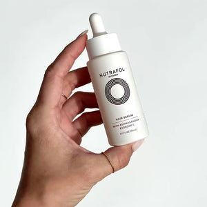Nutrafol Women's Hair Growth Serum bottle in hand shows ashwagandha exosomes for thicker strands and scalp nourishment today