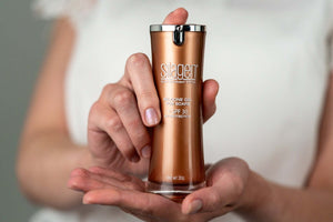 Person holding Silagen silicone scar gel with SPF 30 (30g) bottle, showing pump packaging for daily scar protection.