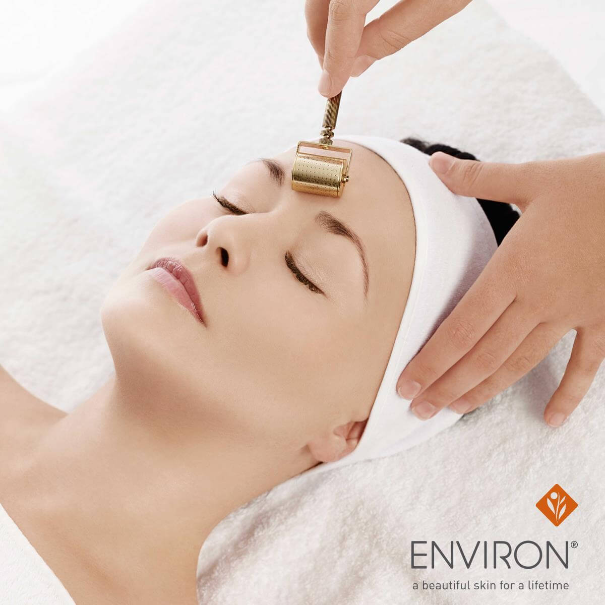Environ Gold Roll-CIT lifestyle — esthetician applying gold microneedle roller to forehead to firm skin and reduce fine lines