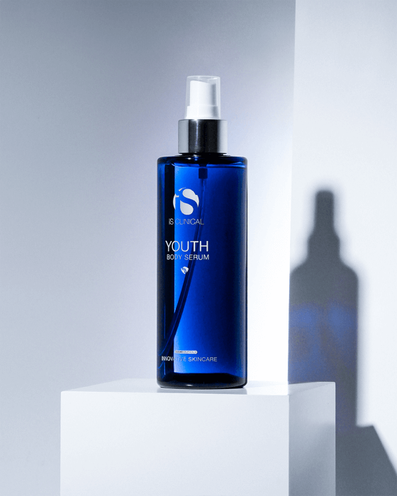 iS Clinical Youth Body Serum blue bottle on white display block with shadow for firming body hydration and smooth skin care.