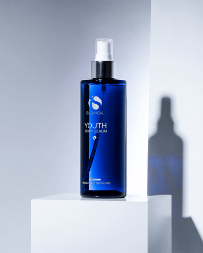 iS Clinical Youth Body Serum blue bottle on white display block with shadow for firming body hydration and smooth skin care.