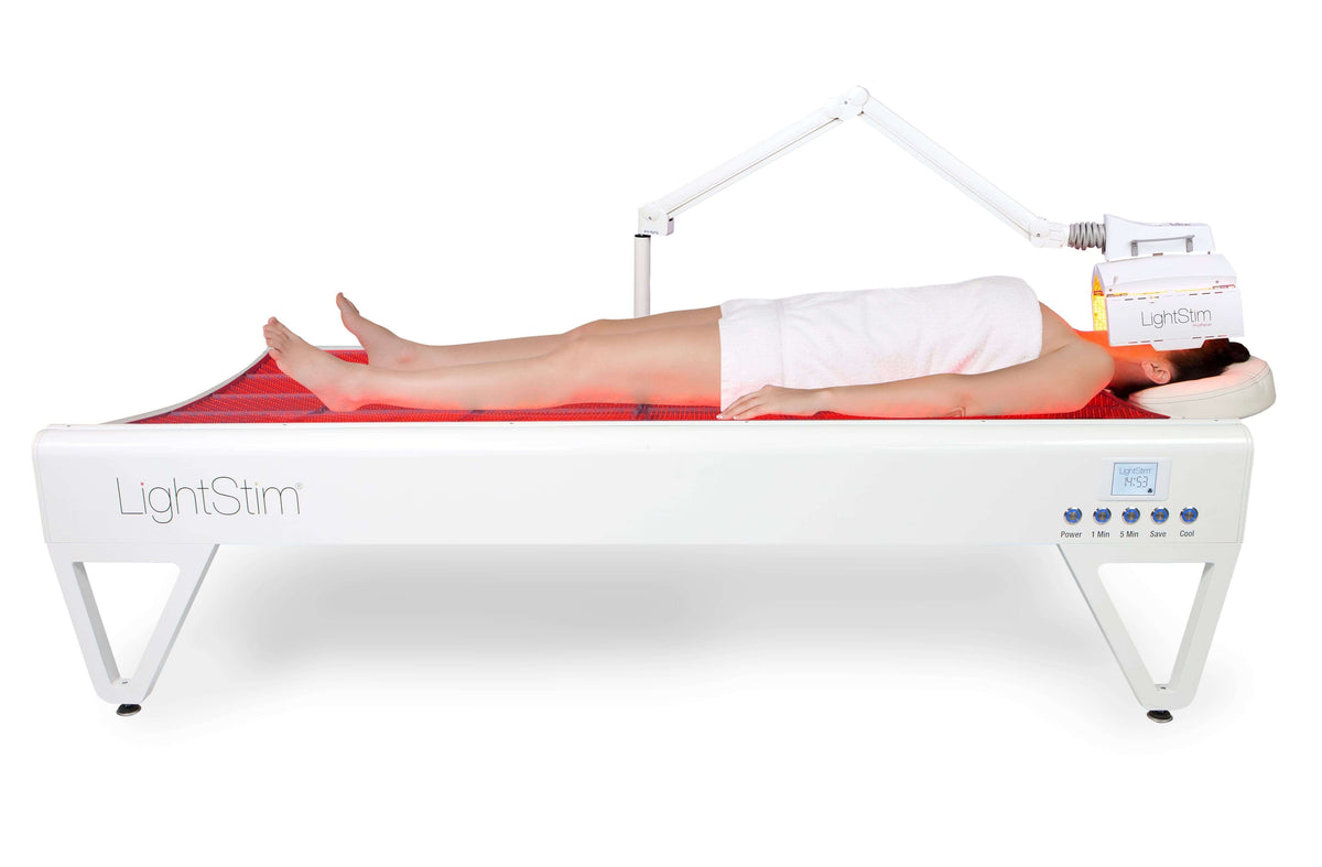 LightStim LED Bed and ProPanel full body red light therapy treatment with client lying on illuminated spa treatment bed area