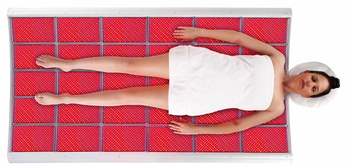 LightStim LED Bed and ProPanel overhead view showing full body red light therapy treatment on glowing LED panels for spa use