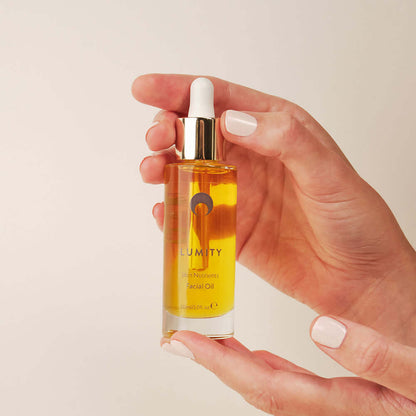 Lumity facial oil 30ml bottle held in hand with golden nutrient oil for smoother hydrated glowing skin and skincare routine.