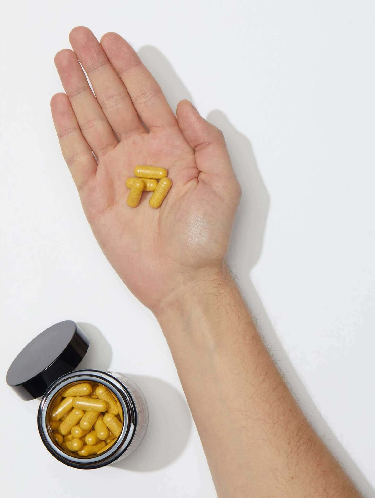 Nutrafol Core for Men capsules in hand show daily hair nutraceutical with saw palmetto, collagen, curcumin, and biotin mix.