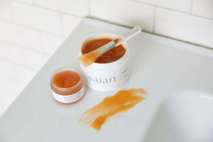 Saian Pumpkin Spice Mask jars with spatula and texture swatch for at-home exfoliating facial treatment routine.