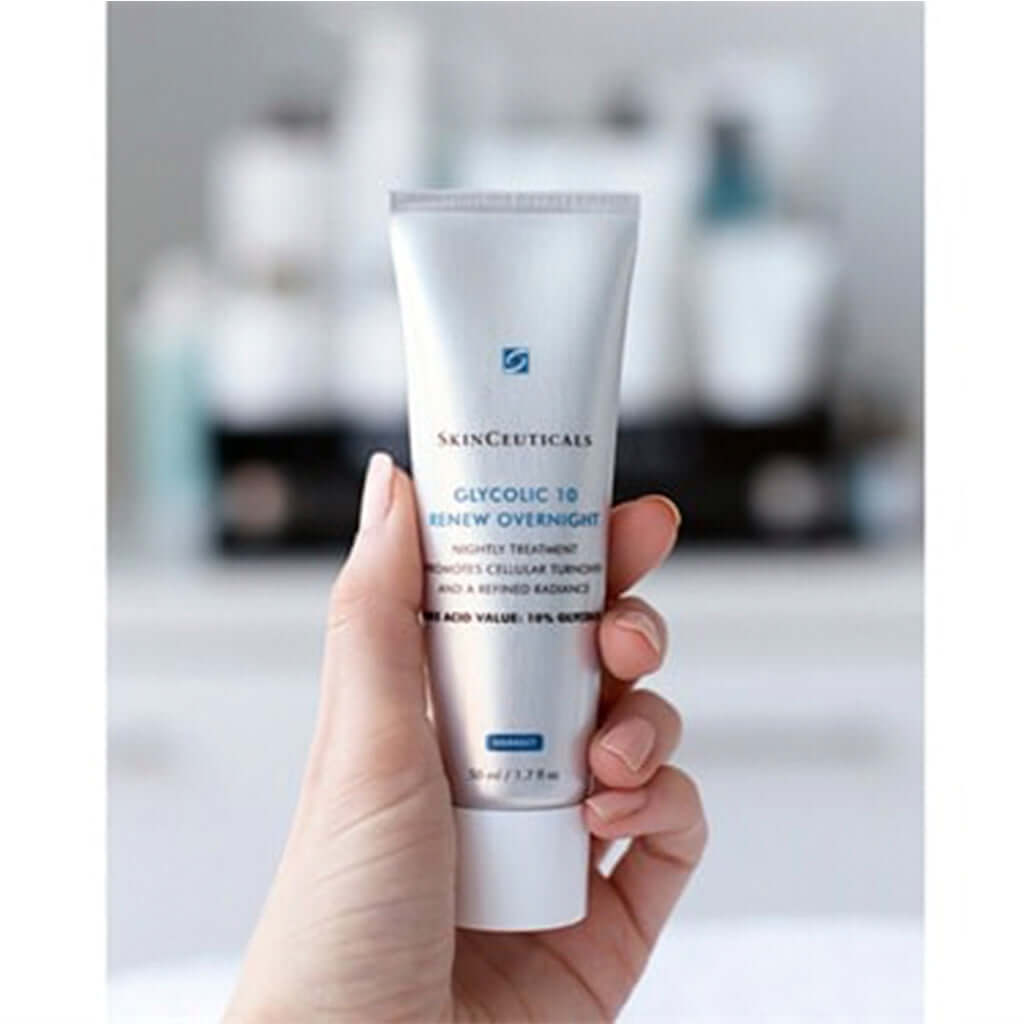 Hand holding SkinCeuticals Glycolic 10 Renew Overnight night treatment tube for smoothing and brightening skin.