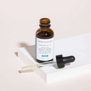 SkinCeuticals Phloretin CF serum bottle with dropper on white block, brightens and evens tone, fades dark spots antioxidant.